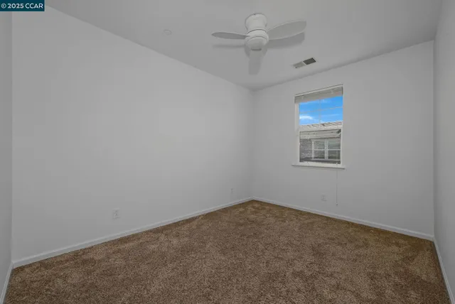 an empty room with a fan & a window