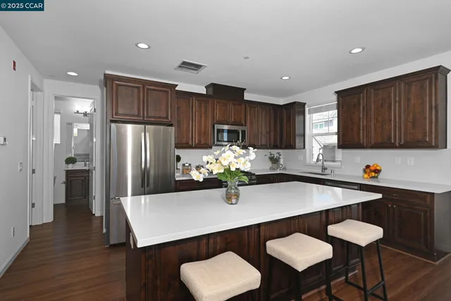 a kitchen with stainless steel appliances a table chairs refrigerator and wooden cabinets