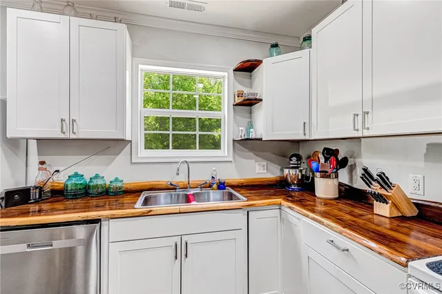 a kitchen with stainless steel appliances granite countertop white cabinets sink and a window