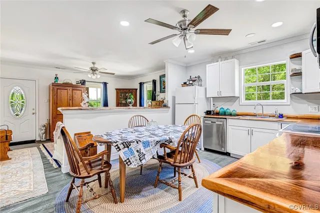 a kitchen with stainless steel appliances kitchen island granite countertop a dining table chairs and a refrigerator
