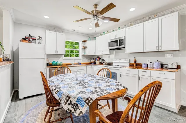 a kitchen with stainless steel appliances granite countertop a dining table chairs refrigerator and microwave