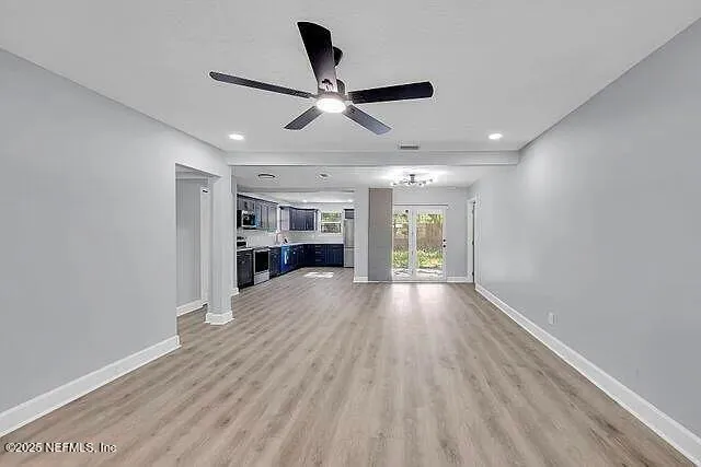 a view of empty room with wooden floor and ceiling fan