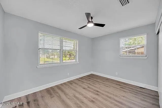 a view of empty room with wooden floor and fan