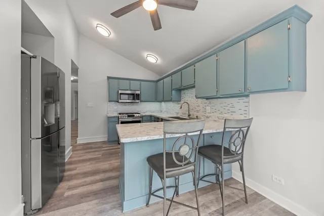 a kitchen with stainless steel appliances granite countertop a sink a stove a refrigerator cabinets a dining table and chairs