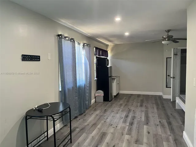 an empty room with wooden floor and a ceiling fan