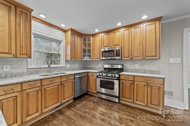 a kitchen with stainless steel appliances granite countertop a stove a sink and a microwave