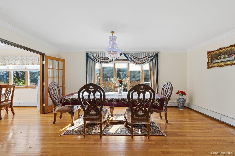 72 Lake End Road Merrick, NY 11566 - Photo 13 of 42 Dining area featuring crown molding, light wood-type flooring, a chandelier, and a baseboard heating unit