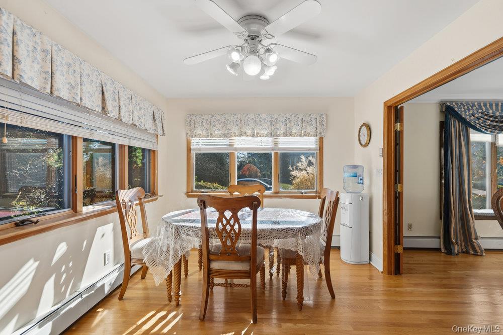 72 Lake End Road Merrick, NY 11566 - Photo 14 of 42 Dining area with baseboard heating, light wood-style floors, and a ceiling fan