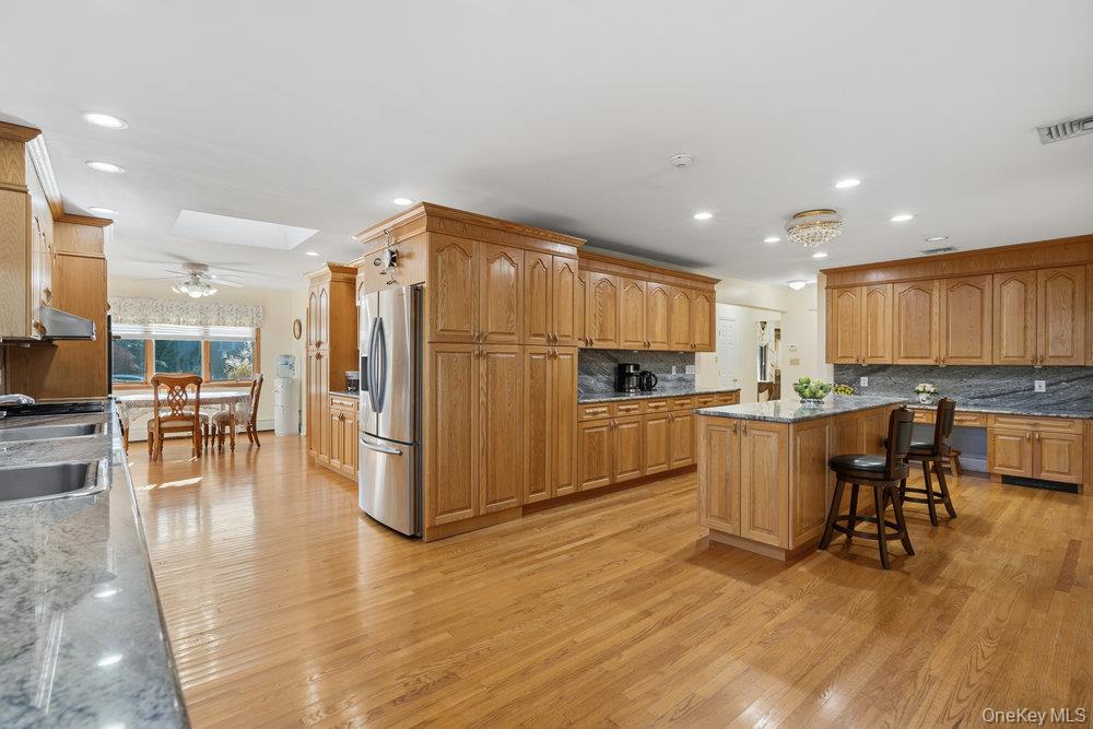 72 Lake End Road Merrick, NY 11566 - Photo 17 of 42 Kitchen with a breakfast bar, a skylight, a kitchen island, stainless steel fridge, and light stone counters