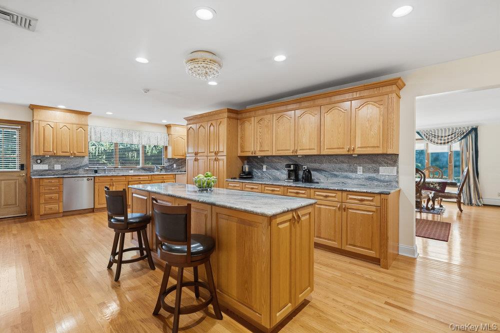 72 Lake End Road Merrick, NY 11566 - Photo 20 of 42 Kitchen featuring light stone counters, a kitchen bar, decorative backsplash, light wood-style floors, and recessed lighting