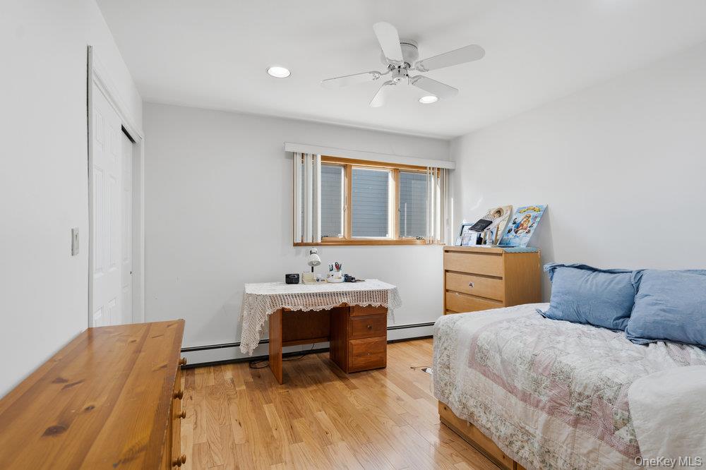 72 Lake End Road Merrick, NY 11566 - Photo 29 of 42 Bedroom featuring light wood-style floors, a closet, a ceiling fan, a baseboard radiator, and recessed lighting