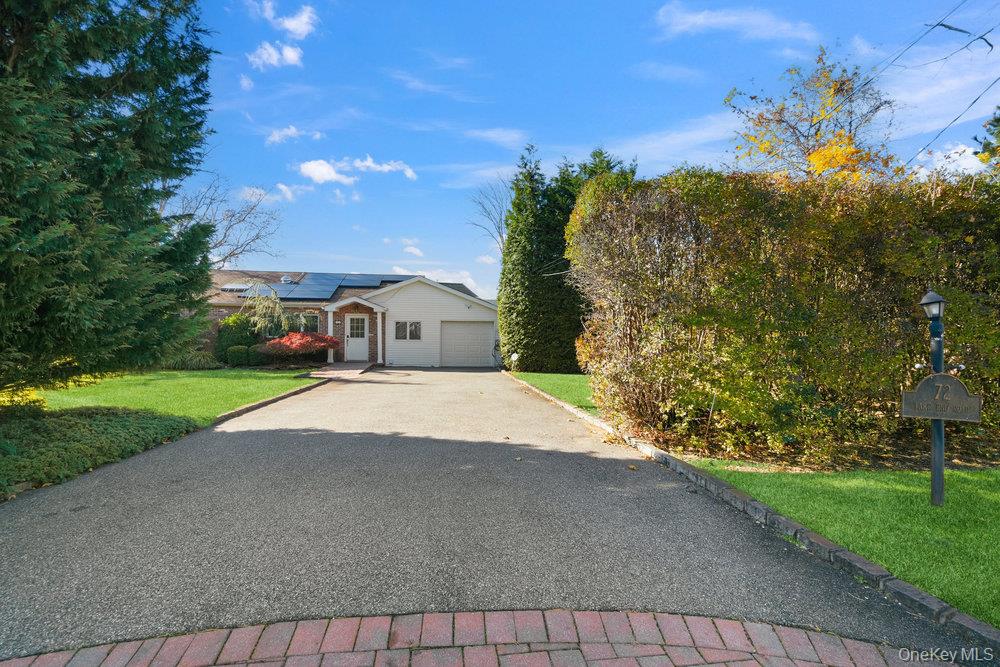 72 Lake End Road Merrick, NY 11566 - Photo 40 of 42 View of front facade with a front lawn, roof mounted solar panels, driveway, and a garage