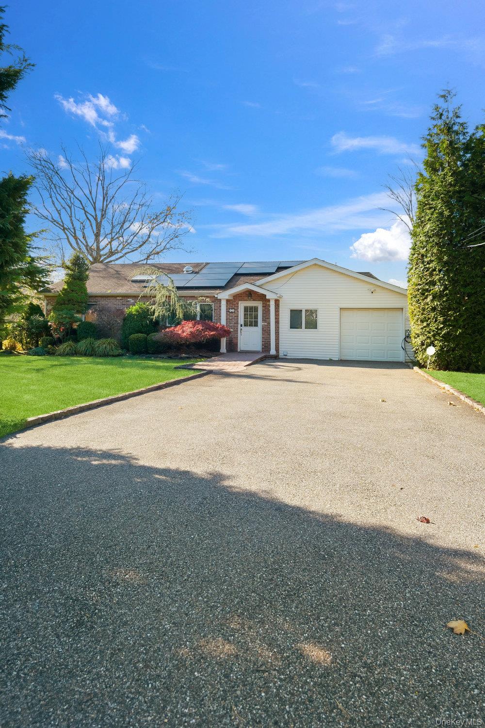 72 Lake End Road Merrick, NY 11566 - Photo 41 of 42 Ranch-style home with solar panels, driveway, brick siding, a front yard, and an attached garage