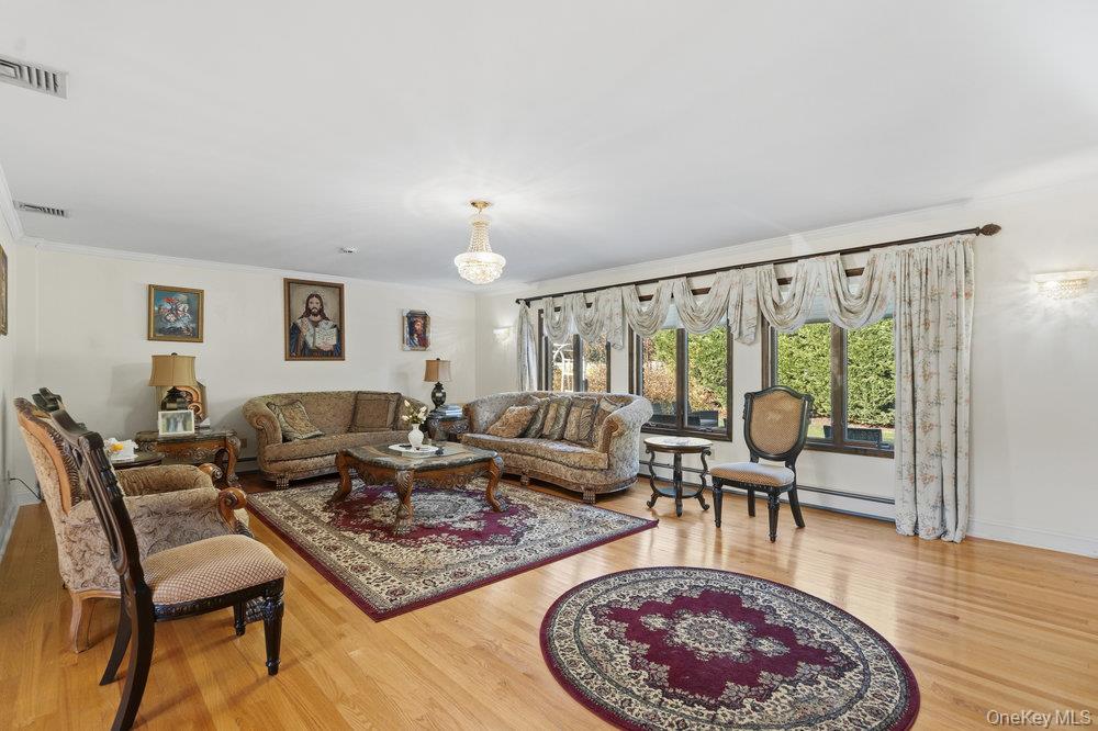 72 Lake End Road Merrick, NY 11566 - Photo 6 of 42 Living room featuring wood finished floors, crown molding, and baseboard heating