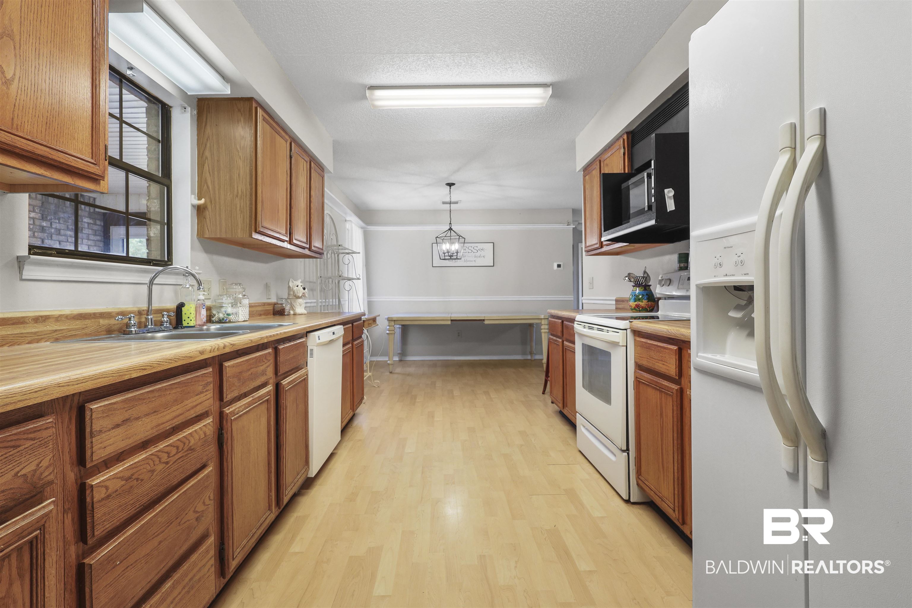 507 West Amanda Avenue Foley, AL 36535 - Photo 16 of 23 Kitchen with hanging light fixtures, sink, white appliances, a textured ceiling, and light wood-type flooring