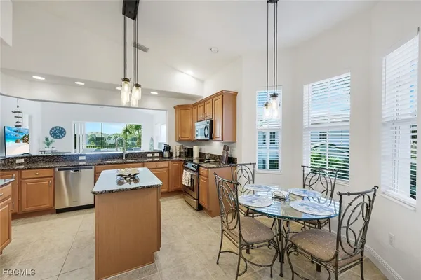 a kitchen with stainless steel appliances granite countertop a kitchen island a table and chairs in it