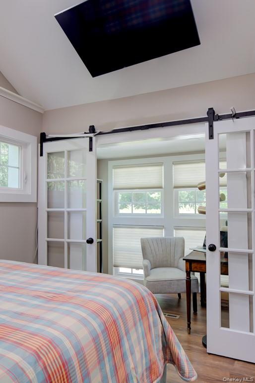 2 Spring Hollow Road Centerport, NY 11721 - Photo 29 of 49 Bedroom featuring a barn door, lofted ceiling, and wood finished floors