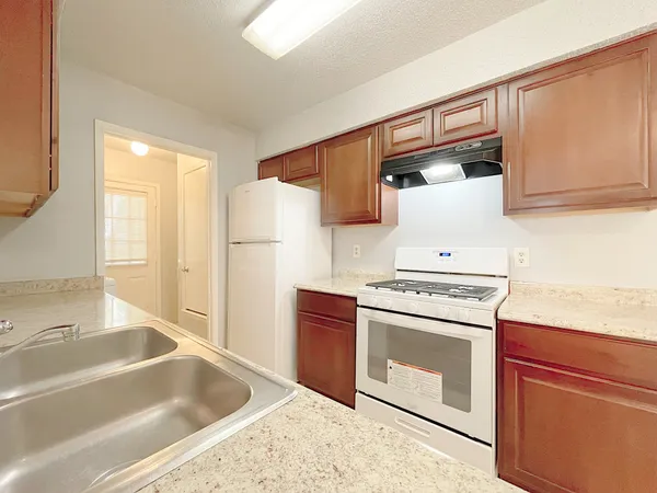 a kitchen with granite countertop a sink stove and refrigerator