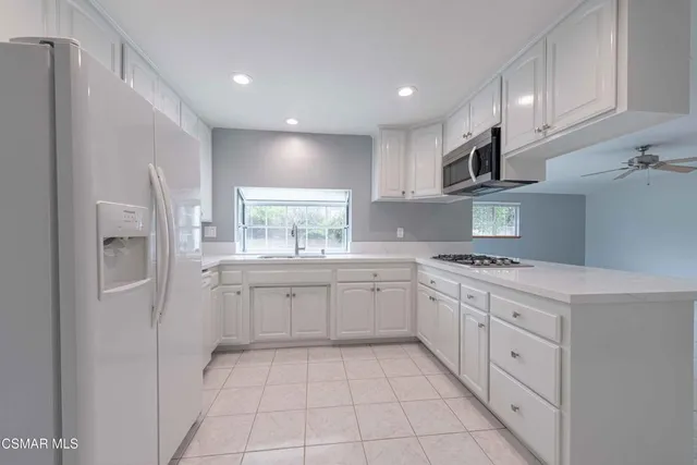 a kitchen with white cabinets stainless steel appliances and a window