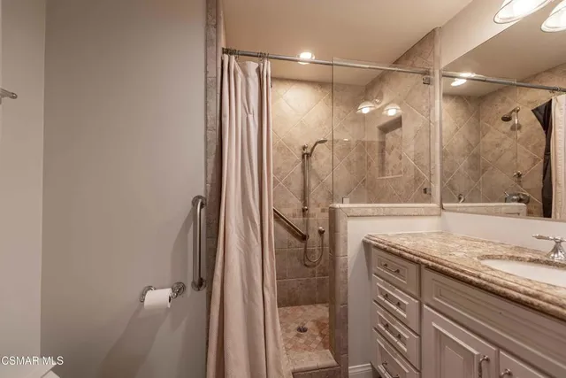 a bathroom with a granite countertop sink a mirror and shower
