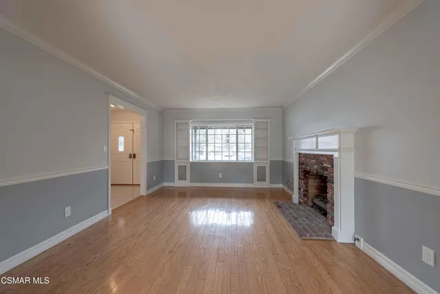 an empty room with wooden floor fireplace and windows