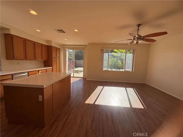 a view of kitchen with wooden floor a sink a refrigerator and a window