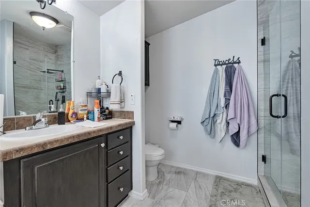 a bathroom with a granite countertop sink a toilet and a shower