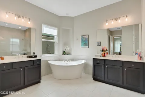a spacious bathroom with a double vanity sink mirror and bathtub
