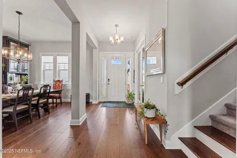 a view of a dining room and livingroom with furniture wooden floor a chandelier