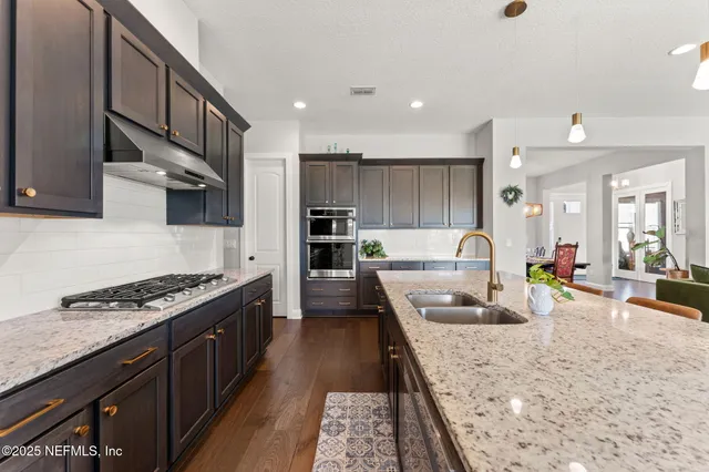 a large kitchen with stainless steel appliances granite countertop a lot of counter space and wooden floors