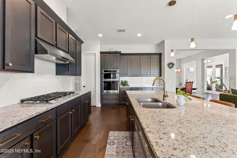 a large kitchen with stainless steel appliances granite countertop a lot of counter space and wooden floors