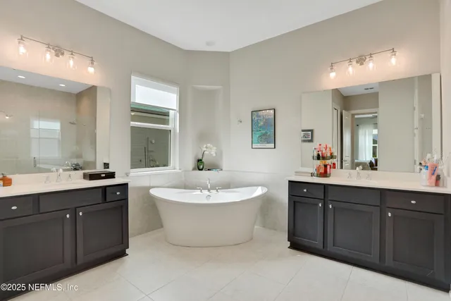 a spacious bathroom with a double vanity sink mirror and bathtub