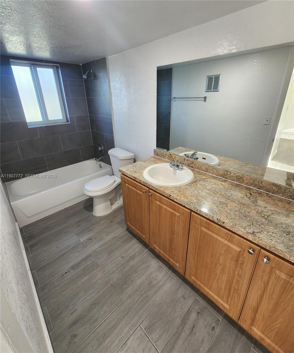 10900 Southwest 196th Street, Unit 213 Cutler Bay, FL 33157 - Photo 12 of 15 a bathroom with a granite countertop sink mirror vanity and toilet