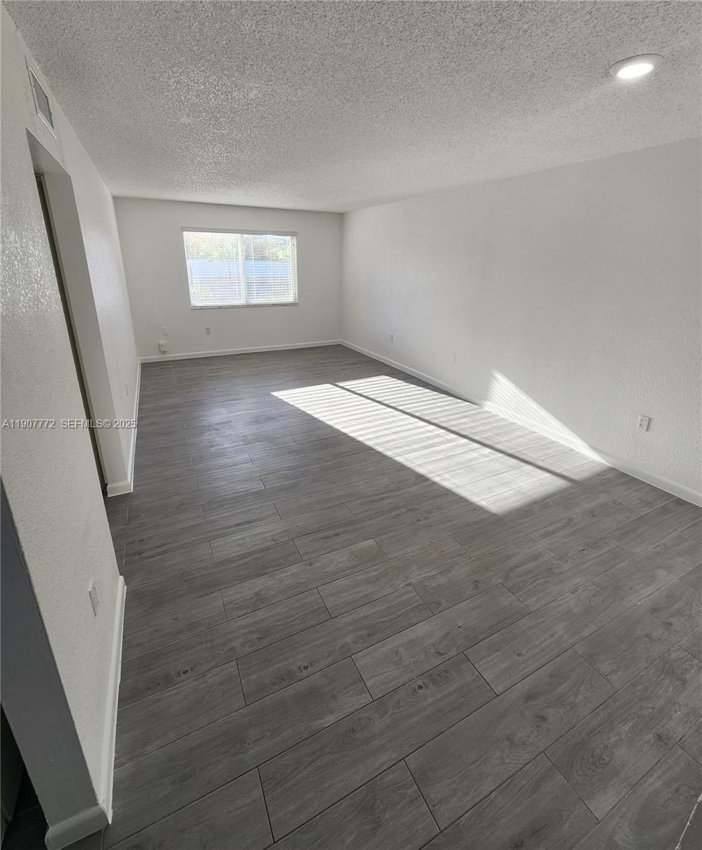 10900 Southwest 196th Street, Unit 213 Cutler Bay, FL 33157 - Photo 5 of 15 an empty room with wooden floor and windows