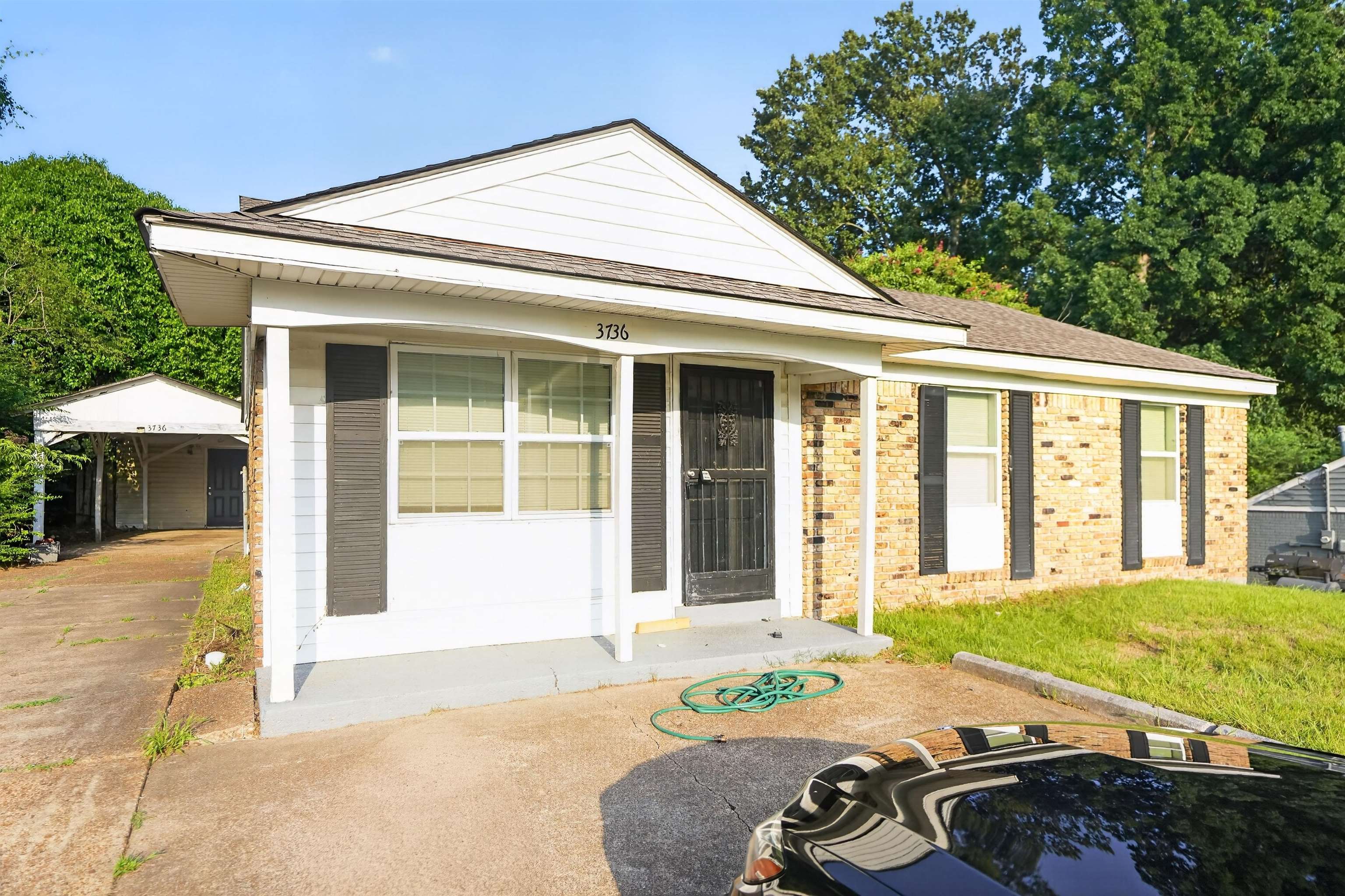 3736 Range Line Road Memphis, TN 38127 - Photo 1 of 18 Brick and siding exterior featuring a covered porch entrance with a security screen door, multiple windows with dark shutters, and a carport