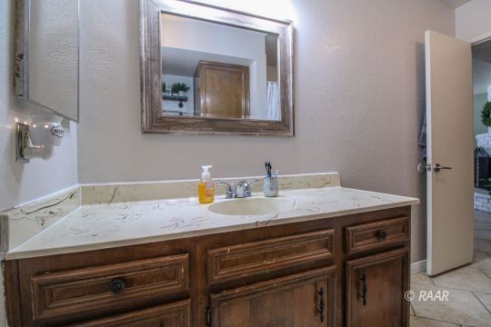 221 South Primrose Street Ridgecrest, CA 93555 - Photo 16 of 29 a bathroom with a granite countertop sink and a mirror