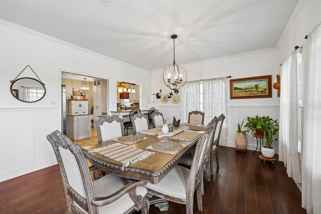 331 Radecke Road Krum, TX 76249 - Photo 12 of 40 Dining area featuring dark wood-finish flooring, white wainscoting, and a decorative chandelier