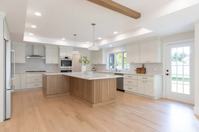 a large kitchen with cabinets wooden floor and stainless steel appliances