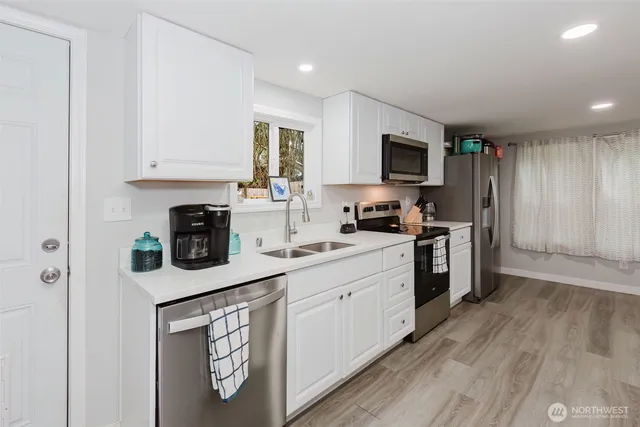 a kitchen with stainless steel appliances granite countertop a stove top oven a sink dishwasher and a refrigerator with wooden floor