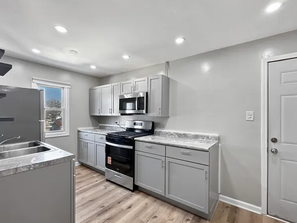 a kitchen with stainless steel appliances granite countertop a stove top oven a sink dishwasher and a refrigerator with wooden floor