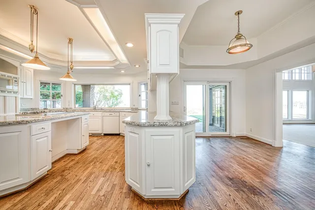 an empty room with chandelier fan and windows