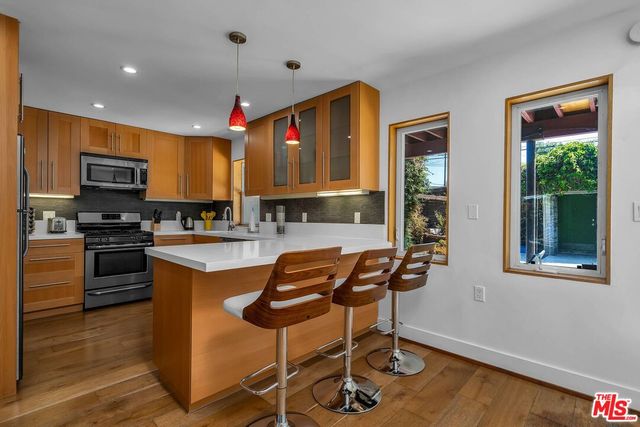 a kitchen with stainless steel appliances granite countertop a stove top oven a sink dishwasher and a microwave oven on the wooden floor