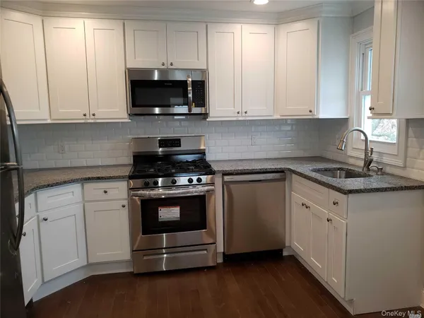 a kitchen with granite countertop white cabinets and stainless steel appliances