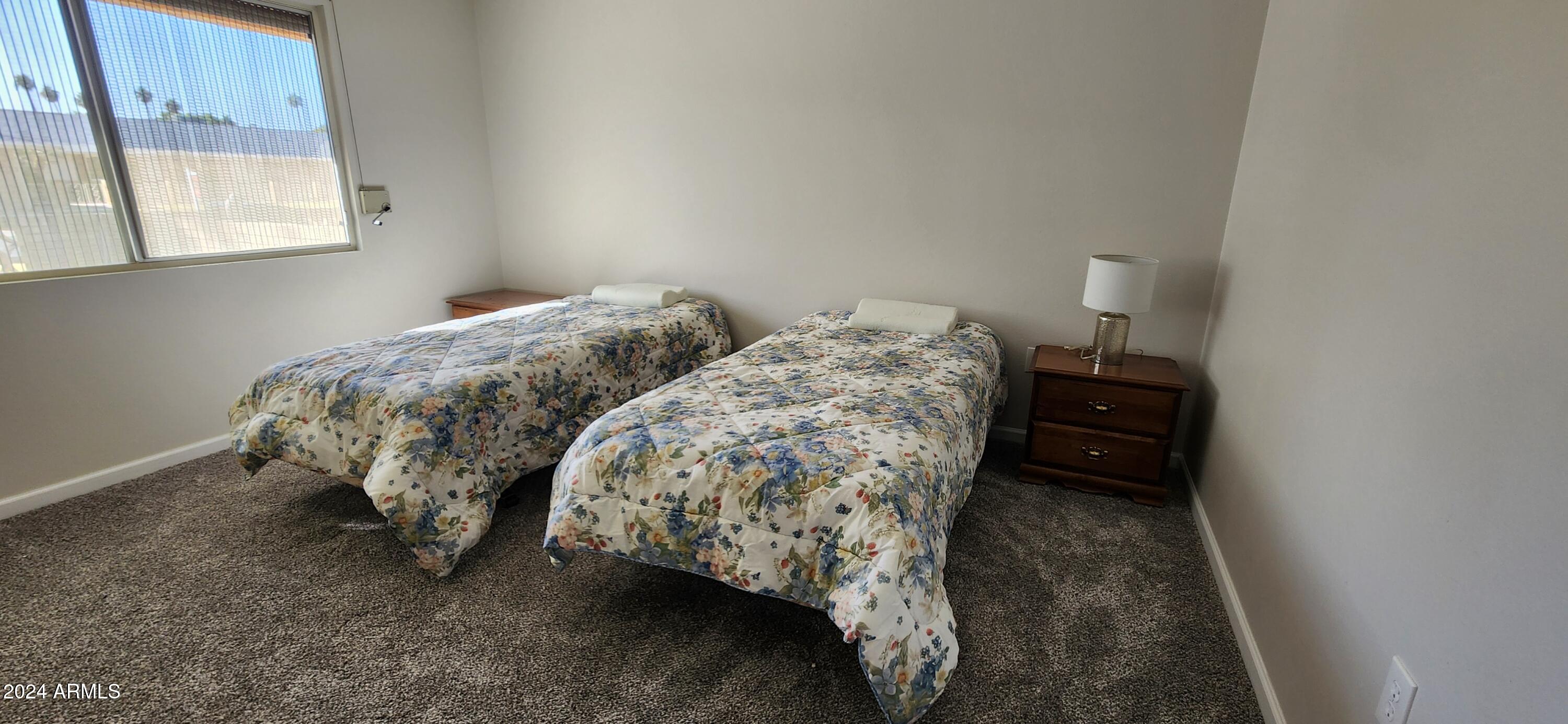 10338 West Kingswood Circle Sun City, AZ 85351 - Photo 18 of 24 a bed sitting in a bedroom next to a window