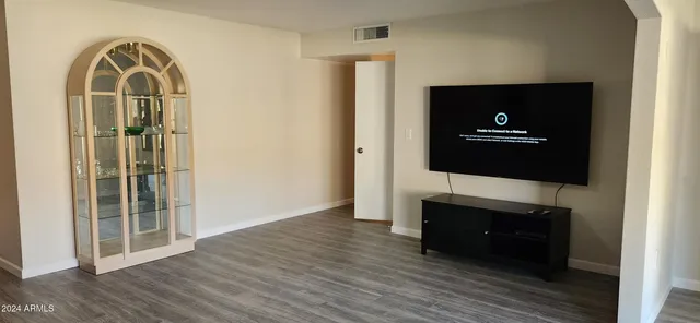 a living room with a flat screen tv and a wooden floor
