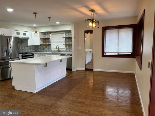 a large kitchen with stainless steel appliances granite countertop a stove a sink dishwasher and a refrigerator with wooden floor