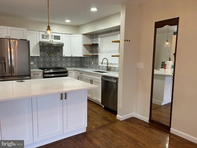a kitchen with kitchen island granite countertop a sink cabinets and stainless steel appliances