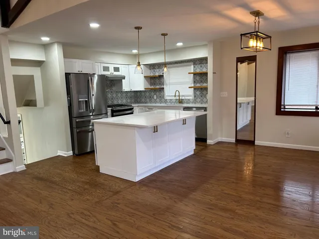 a large kitchen with stainless steel appliances kitchen island a large counter top and wooden floors