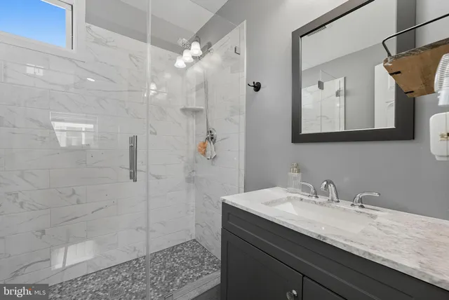 a bathroom with a granite countertop sink a mirror and shower