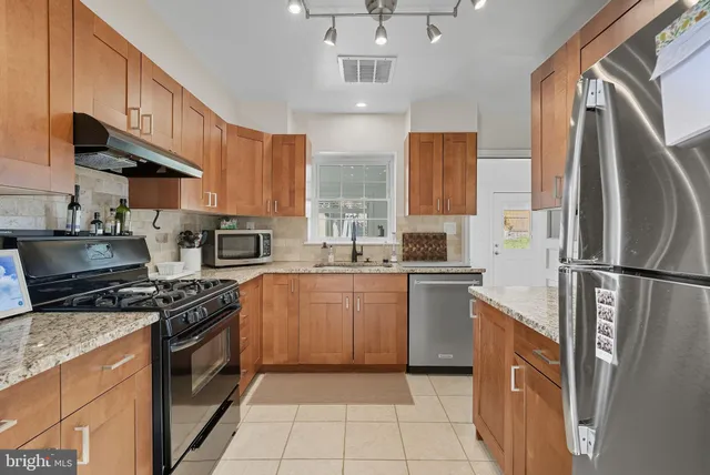 a kitchen with stainless steel appliances granite countertop a stove top oven a sink and a refrigerator